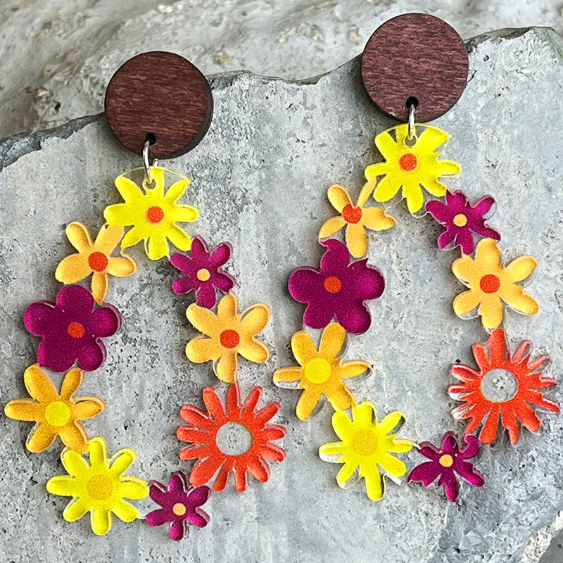 Floral wreath dangle earrings with wood tops, featuring colorful acrylic flowers in yellow, orange, and magenta.