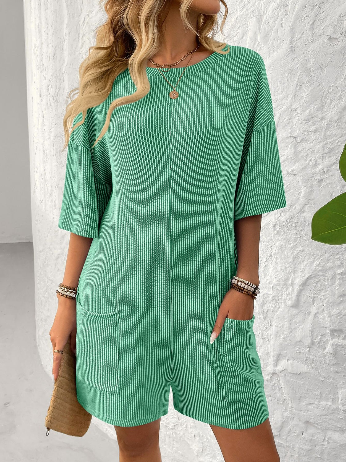 Green ribbed knit romper with short sleeves, crew neck, and front pockets.
