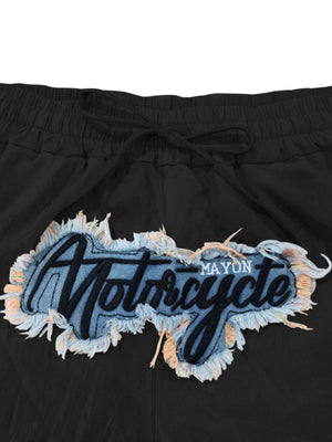 Black sweatpants with drawstring and embroidered motorcycle graphic patch.