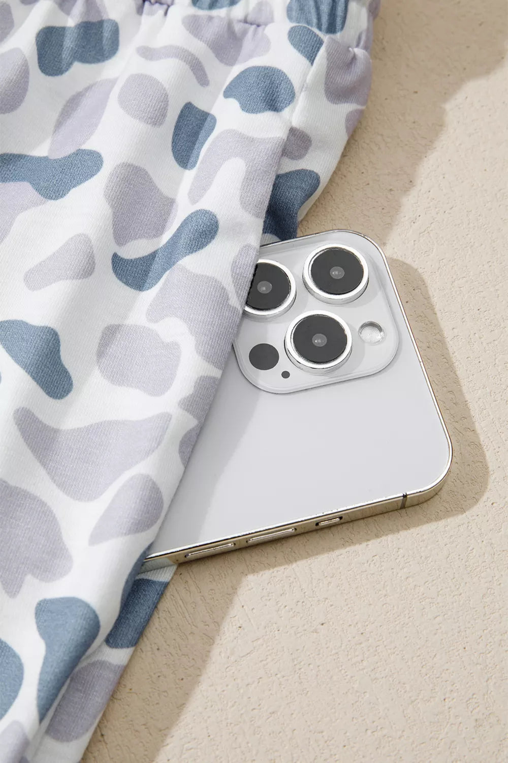 Camouflage print pajama pants in blue and grey with a white background, showing a side pocket detail.