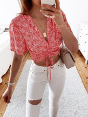 Red petal print ruched crop top with V-neck and short sleeves.