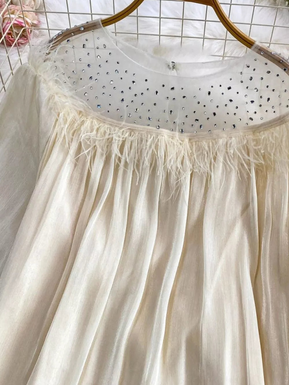 Apricot sheer mesh blouse with rhinestone-embellished neckline and feather trim.