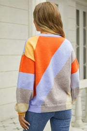 Geometric colorblock knit crewneck sweater with orange, blue, yellow, and tan panels.