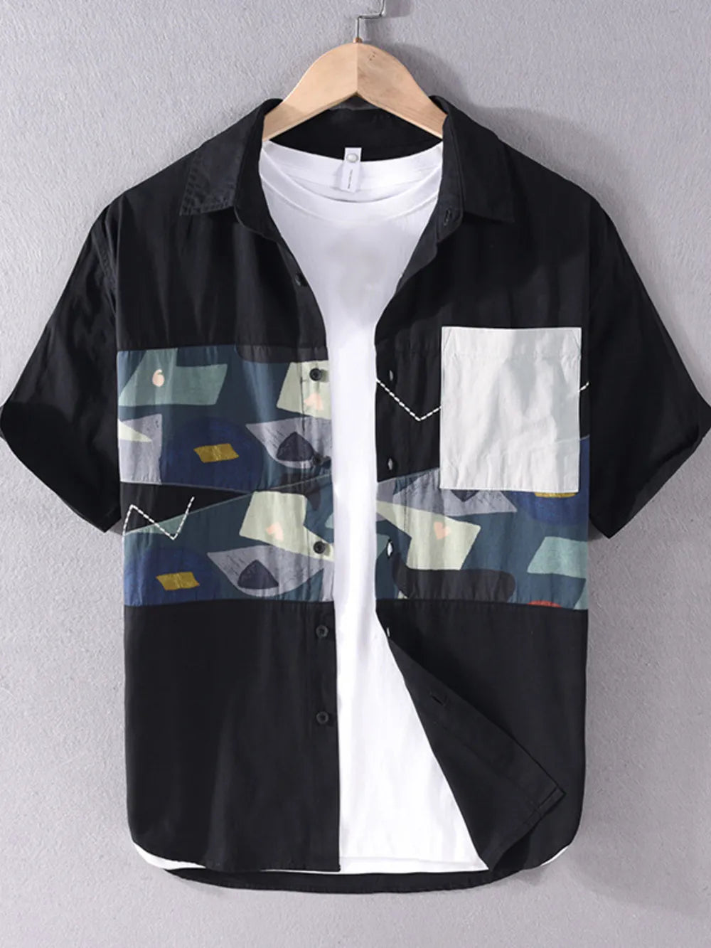 Men's black short sleeve button-down shirt with geometric print panel and white chest pocket.