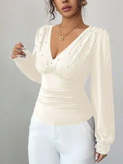 Beige ruched V-neck blouse with pearl embellishments and long sleeves.