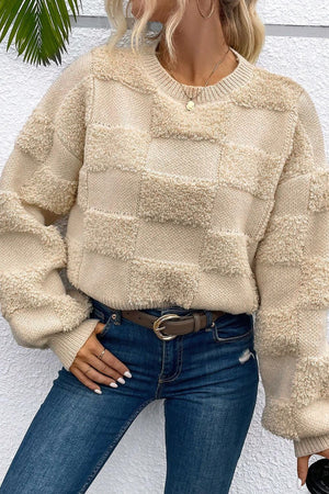 Beige checkerboard knit sweater with textured squares, crewneck, and long sleeves.