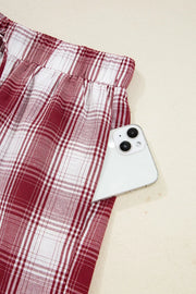 Pajama pants with red and white plaid pattern and a pocket holding a smartphone.