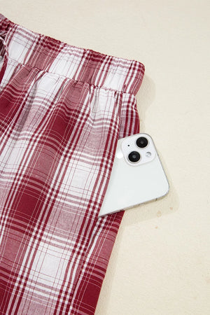 Pajama pants with red and white plaid pattern and a pocket holding a smartphone.
