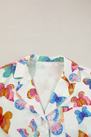 White pajama set with colorful butterfly print, featuring a classic collar and button-up detail.