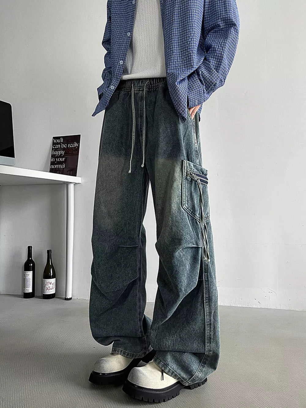 Relaxed fit blue denim cargo jeans with drawstring waist and zippered pockets.