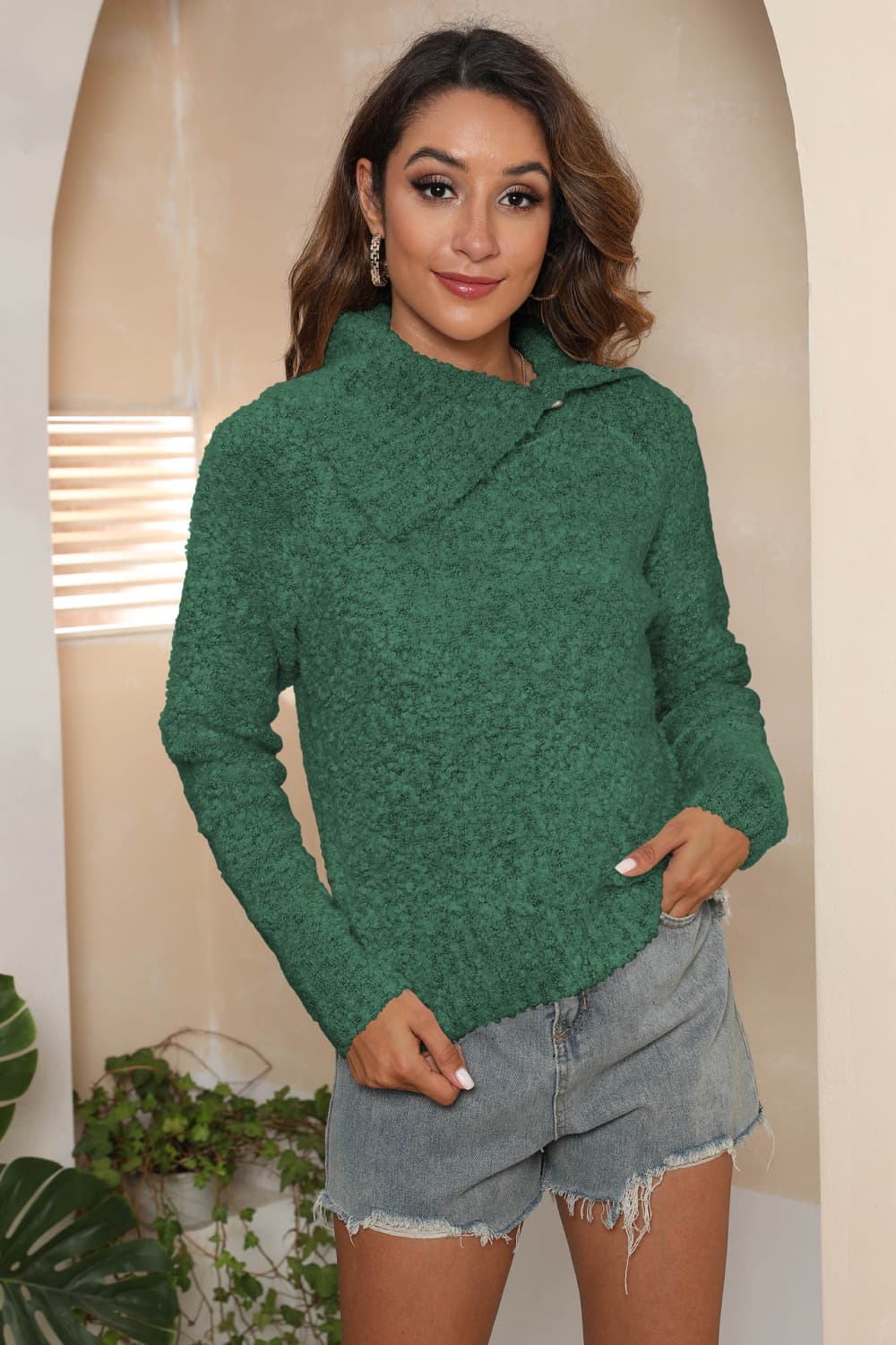 Dark green textured knit sweater with an asymmetric collar and button detail.