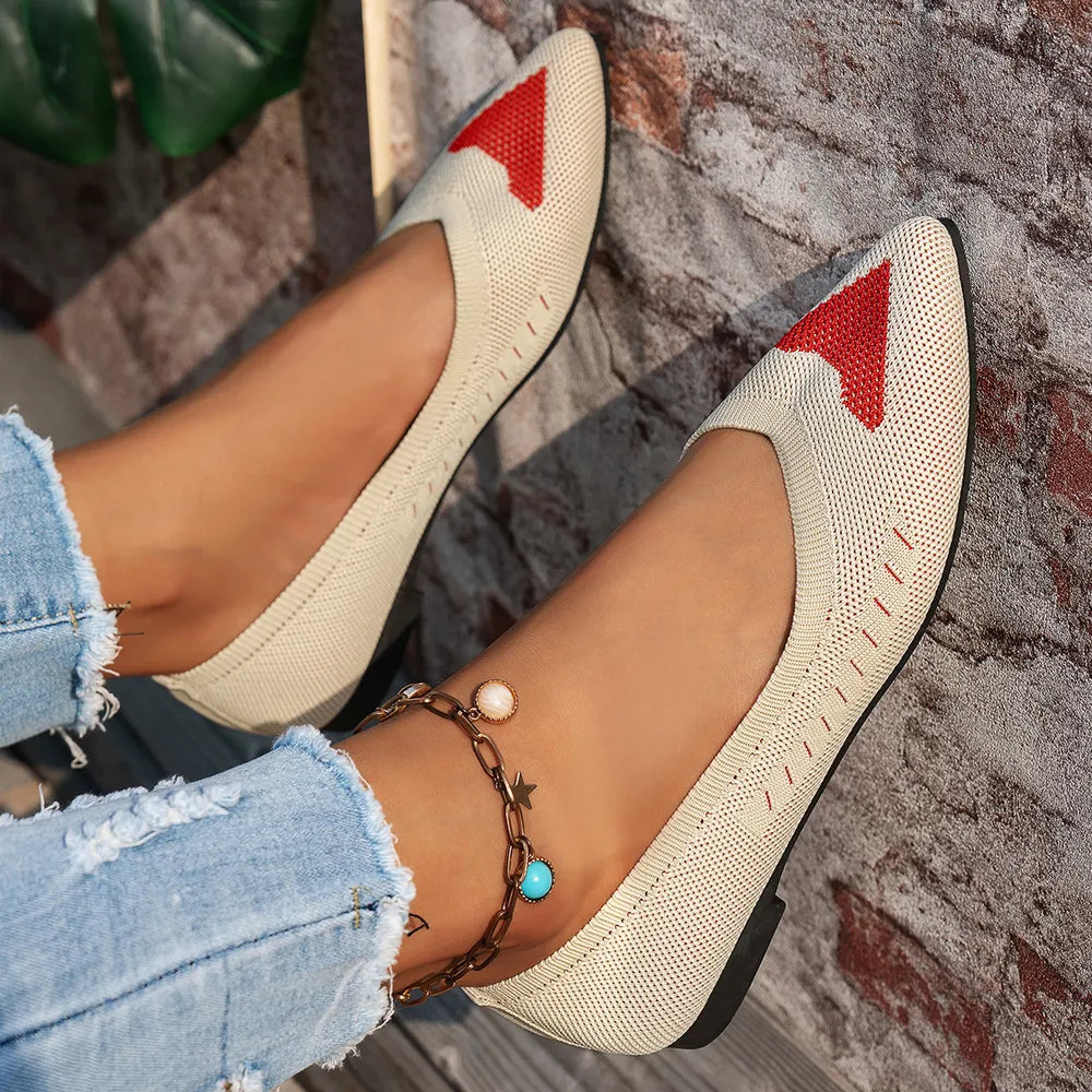 Beige knit pointed flats with red geometric detail and red stitching.