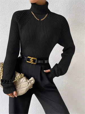 Black ribbed turtleneck sweater with ruffled cuffs and a gold chain necklace.