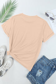 Tan t-shirt with rolled sleeves and a knotted hem, styled with denim shorts and sneakers.
