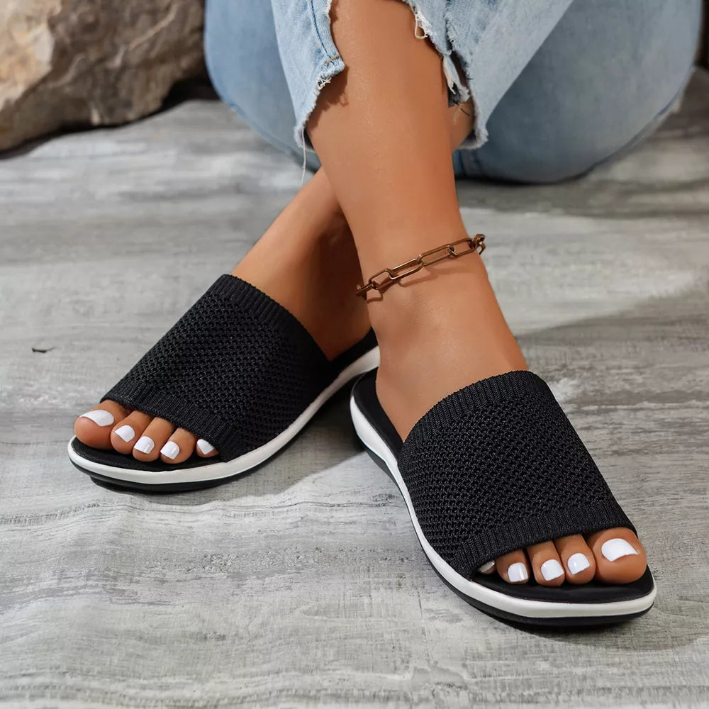 Black open-toe knit slide sandals with white-trimmed soles.