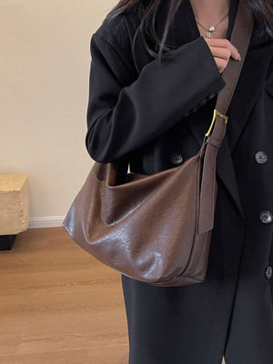 Brown faux leather shoulder bag with adjustable strap and gold buckle detail.