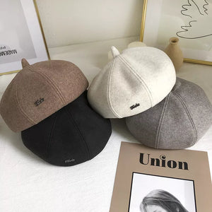 Woolen beret with paneled design in ivory, black, and beige.
