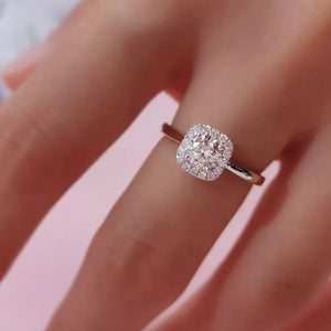 Elegant moissanite and sterling silver ring with cushion-cut center stone and halo detail.