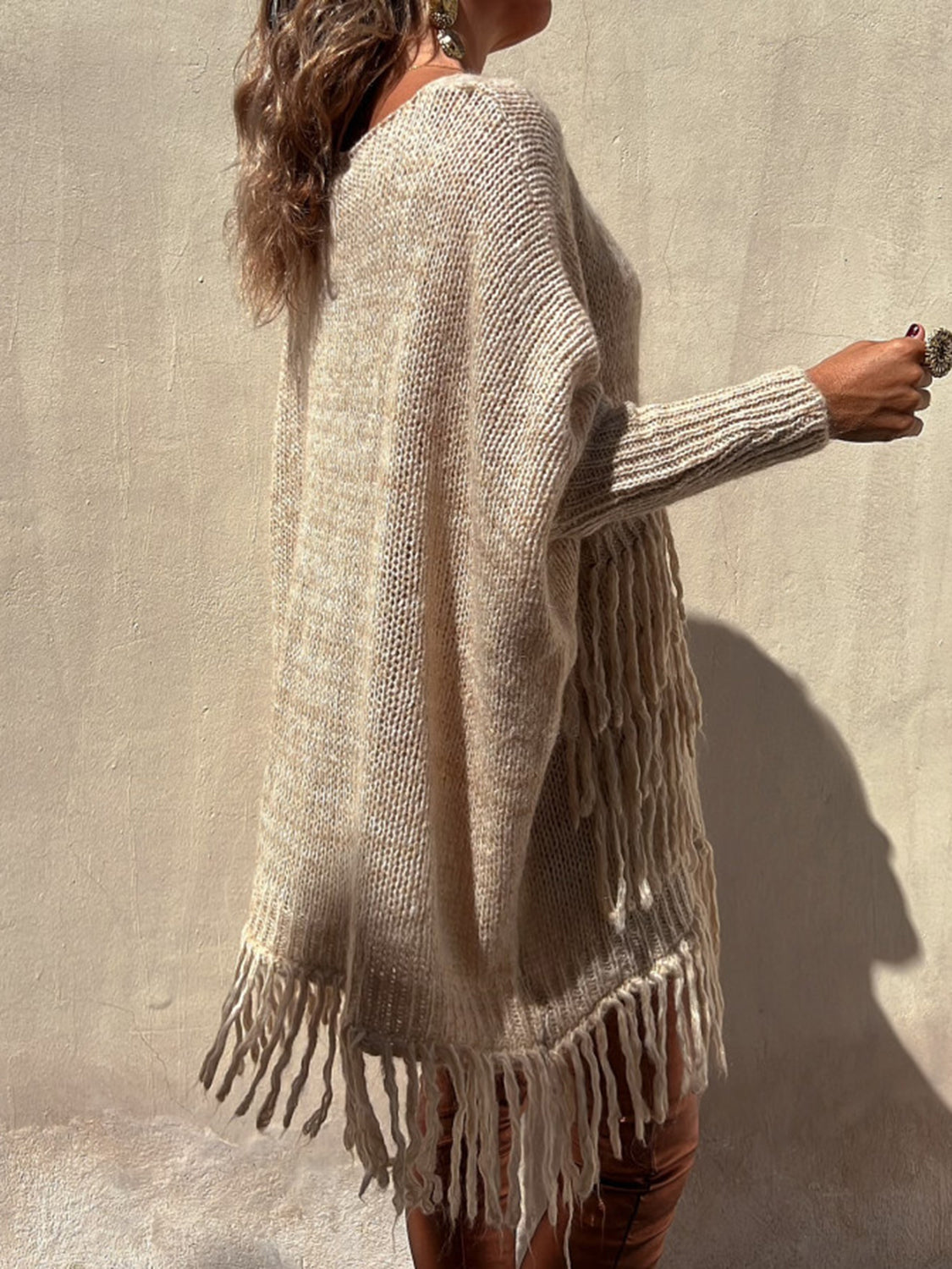 Camel knit poncho sweater with fringe detail and long sleeves.