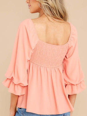 Watermelon pink babydoll blouse with square neckline, smocked back, and ruffled bell sleeves.