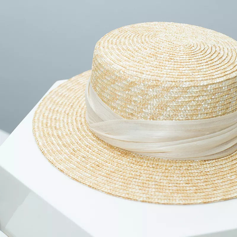 Elegant straw boater hat in tan with a sheer ribbon trim.
