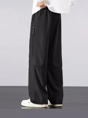 Men's black loose fit cargo pants with zippered pocket detail.