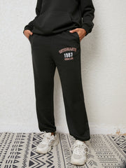 Black graphic joggers with "ENTHUSIASTIC 1987 REMAIN" text detail.