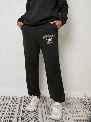Black graphic joggers with "ENTHUSIASTIC 1987 REMAIN" text detail.