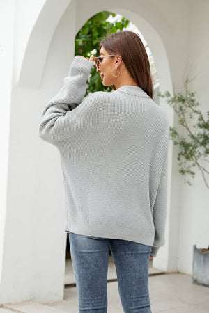 Oversized grey waffle knit cardigan with button front, worn with jeans.