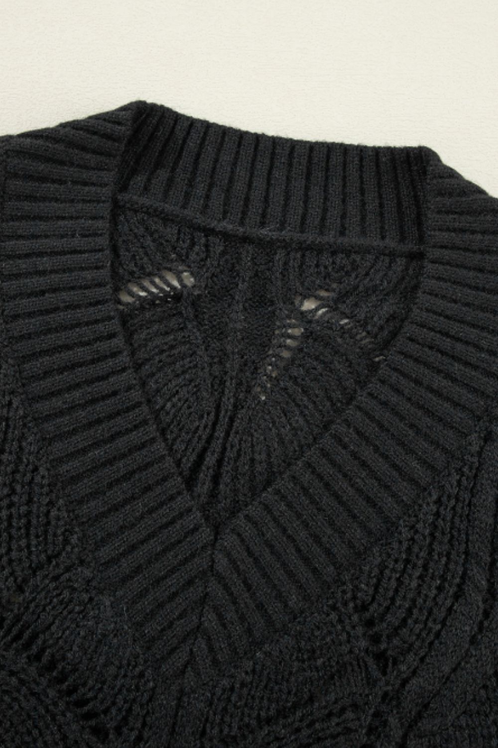 Black openwork knit V-neck pullover sweater with textured stitch details.