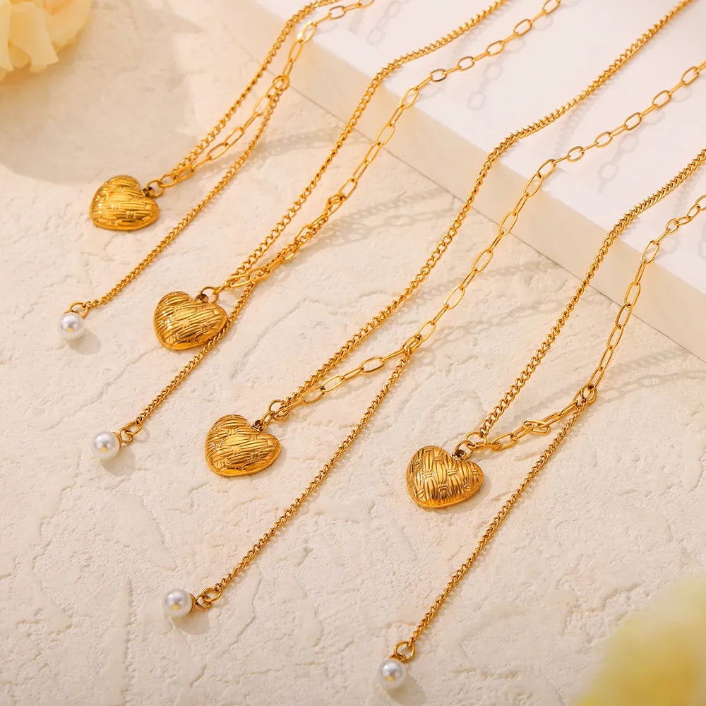 Gold textured heart and pearl drop necklaces, layered chains, elegant jewelry.