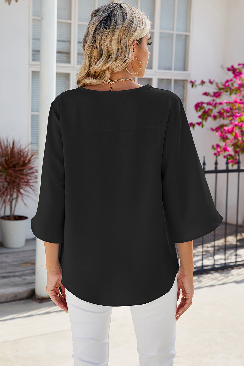 Black asymmetric sleeve blouse with a relaxed fit and curved hem.