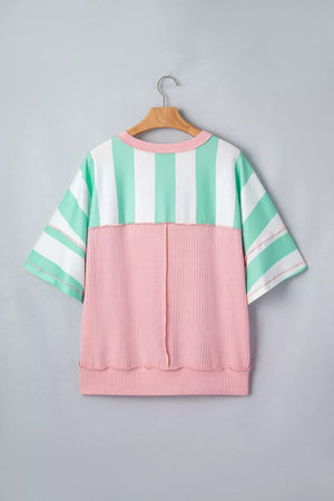 Oversized t-shirt with pastel stripes and pink ribbed panel, exposed seams.