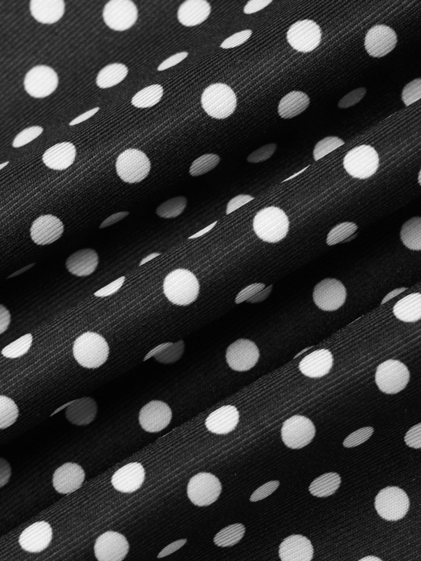 Black and white polka dot fabric detail of a ruffled crop top and skirt set.