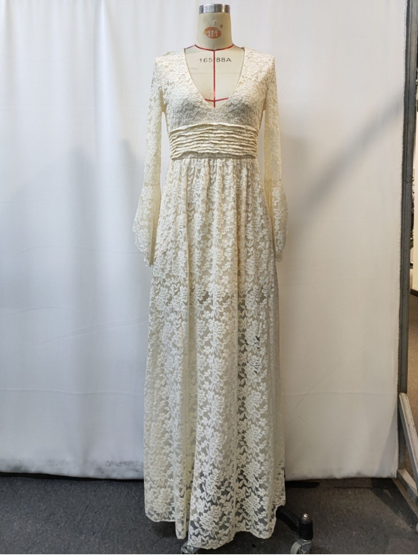 Cream lace maxi dress with deep V-neck, long bell sleeves, and ruched waist detail.