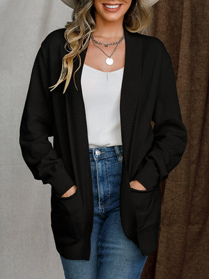 Black textured knit open-front cardigan with pockets, styled with a white tank and jeans.