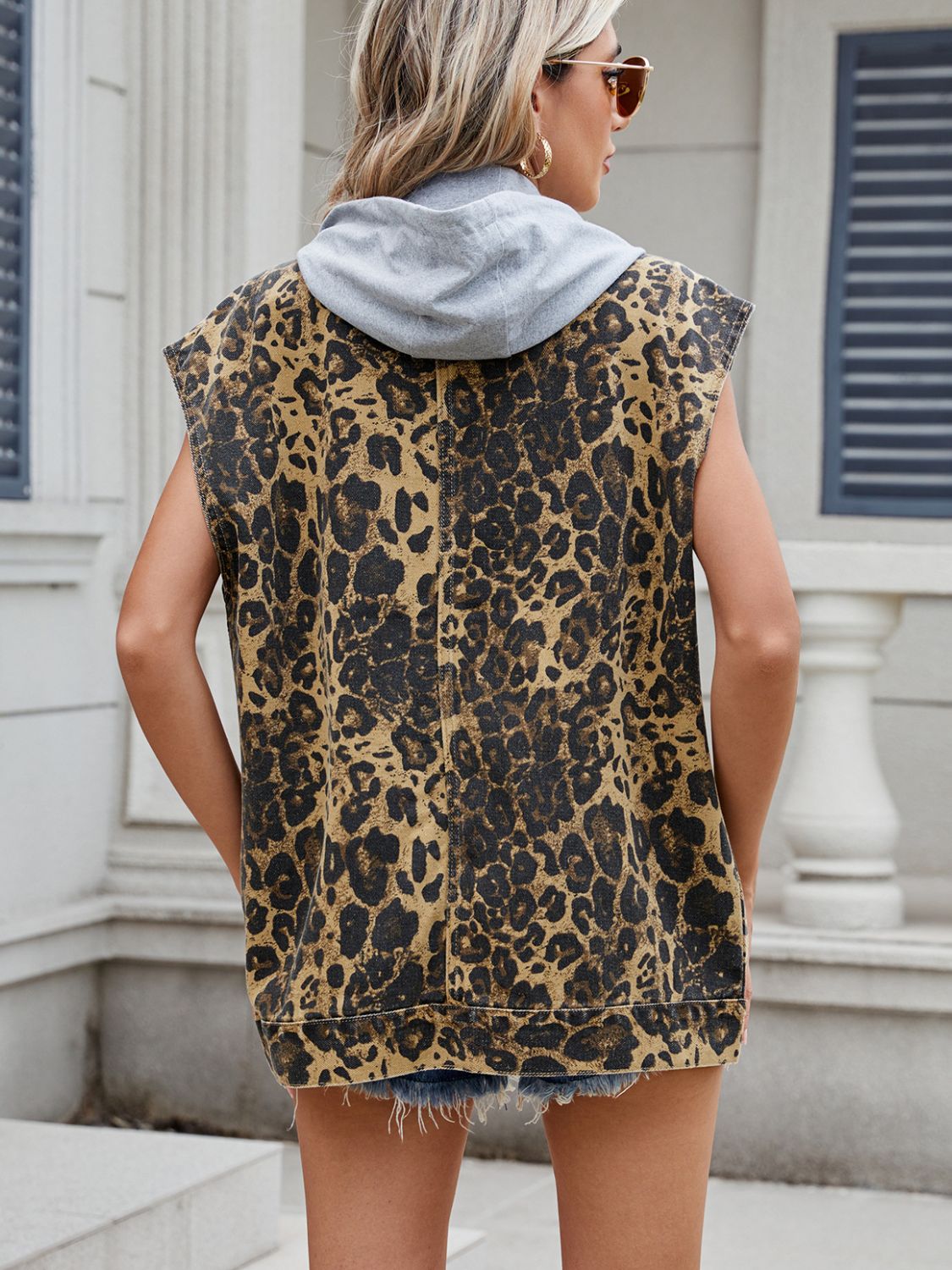 Leopard print denim utility vest with a grey removable hood, sleeveless.