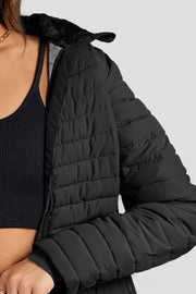 Black quilted stand collar puffer jacket with faux fur trim detail.