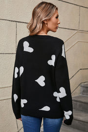 Black acrylic knit jumper with scattered white hearts pattern, crew neck, long sleeves.