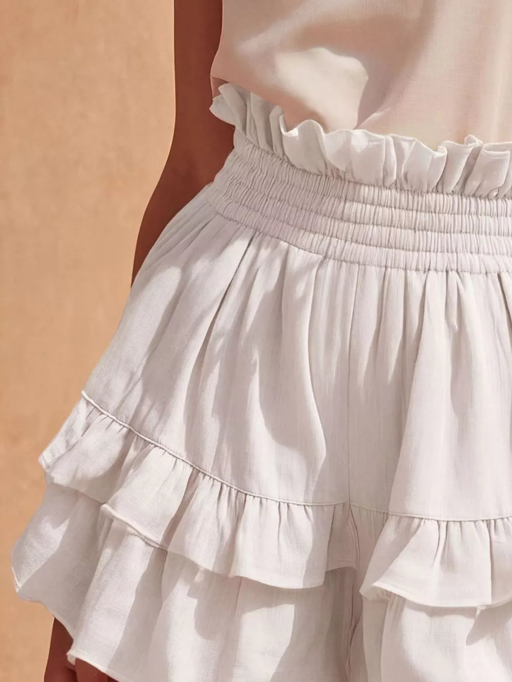 White ruffled high-waisted shorts with smocked waistband and tiered ruffles.