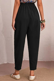 Black linen tapered trousers with elastic waist and cuffed hem.