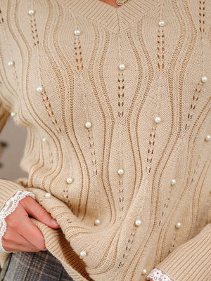 Beige V-neck knit sweater with pearl details and lace cuffs.