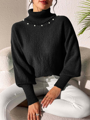 Black knit sweater with dolman sleeves, turtleneck, and pearl embellishments.