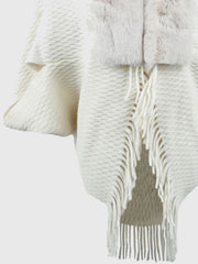 White textured knit poncho with faux fur collar and fringe detail