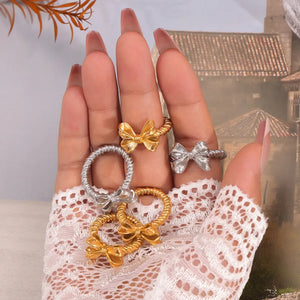 Textured bow knot rings in silver and gold, featuring a twisted band detail.