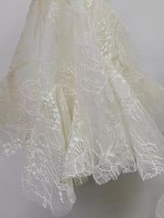 White floral lace dress detail with ruffle hem and subtle sequins.