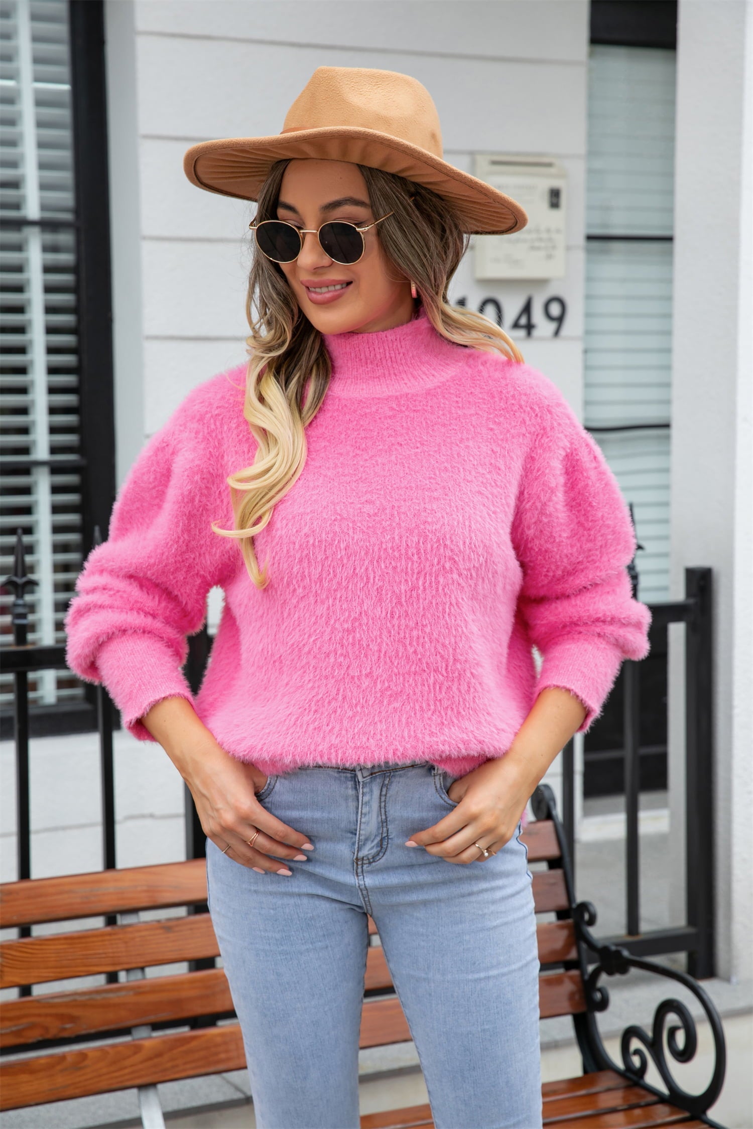 Pink fluffy mock neck sweater with long sleeves, styled casually with jeans.