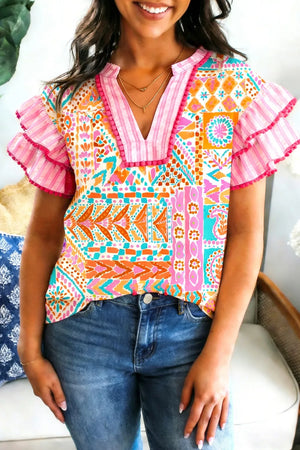 Vibrant patchwork blouse with ruffle sleeves and pink trim detail.