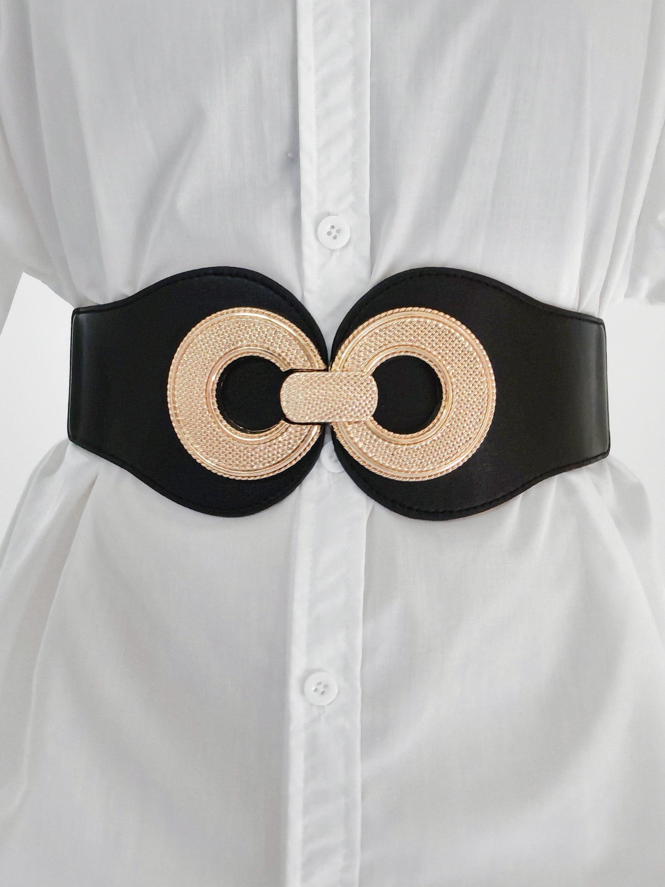 Black cincher belt with gold metalwork detail, worn over a white shirt.