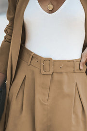 Camel double-breasted blazer and pleated shorts set with a matching belt and white tank top.